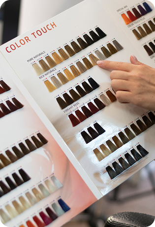 Carta de color de tintes capilares con múltiples muestras de tonalidades, donde una persona señala un tono específico para elegir el color deseado con precisión y asesoramiento profesional.