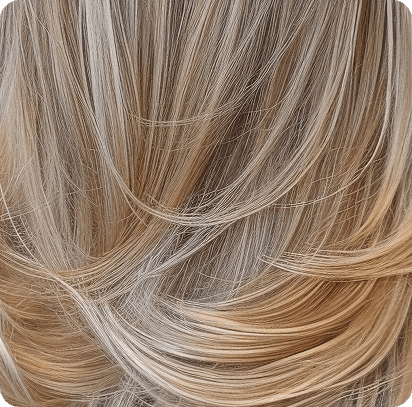 La imagen muestra un cabello rubio con un acabado natural y con mucho movimiento. El cabello tiene una mezcla de tonos cálidos y fríos, lo que crea un hermoso efecto degradado desde las raíces hacia las puntas. Las capas se mezclan suavemente, aportando volumen y textura, lo que da un look fluido y lleno de vida. Este estilo es ideal para quienes buscan un toque sofisticado y luminoso en su melena.